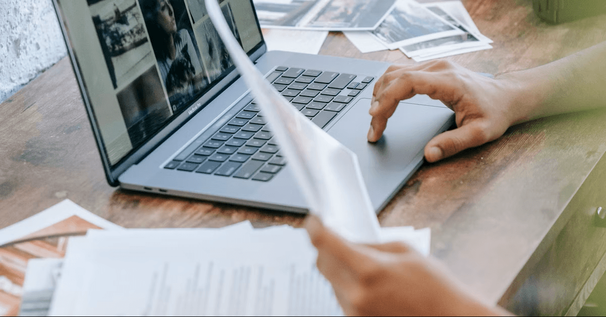 A person reviewing printed documents next to a laptop, illustrating PDF and document accessibility